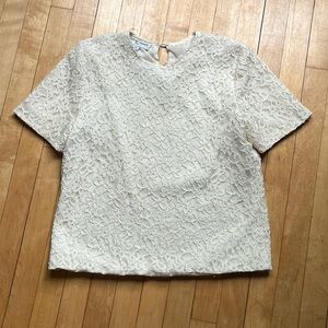 White blouse with textured floral pattern.